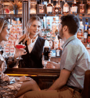 Guests enjoy drinks at the Arlington Hotel bar with a friendly bartender.