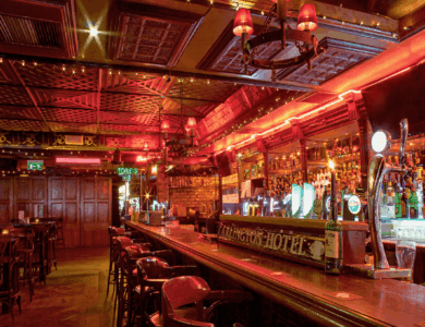Warm, cosy bar at the Arlington Hotel with vintage wooden decor and glowing red lights.