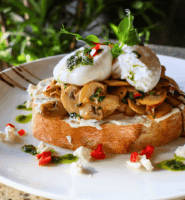 Gourmet mushroom bruschetta with poached eggs in a garden setting.