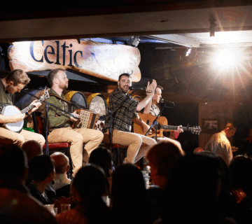 Musicians perform on stage at a lively Dublin bar, engaging a cheerful crowd.