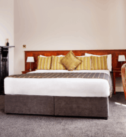 Elegant hotel room with plush bed, cosy fireplace, and tasteful decor.