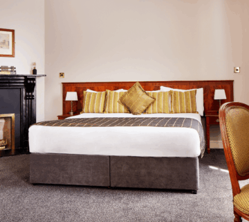 Elegant hotel room with plush bed, cosy fireplace, and tasteful decor.