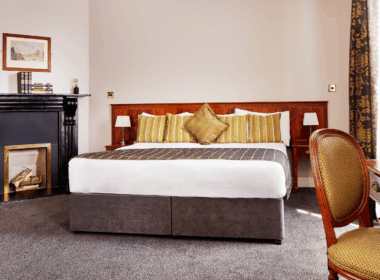 Elegant hotel room with plush bed, cosy fireplace, and tasteful decor.