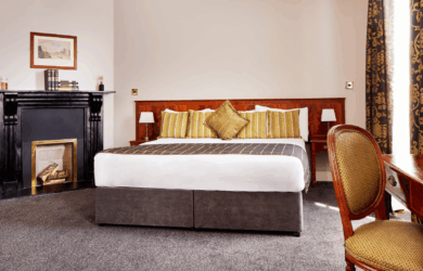 Elegant hotel room with plush bed, cosy fireplace, and tasteful decor.