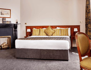 Elegant hotel room with plush bed, cosy fireplace, and tasteful decor.