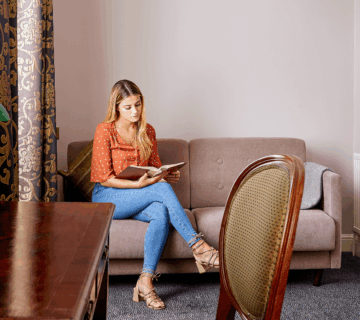 Woman relaxes on sofa with a book in a cosy hotel room