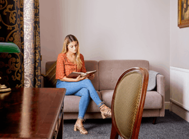Woman relaxes on sofa with a book in a cosy hotel room