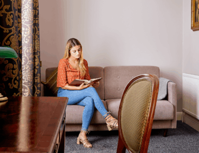 Woman relaxes on sofa with a book in a cosy hotel room