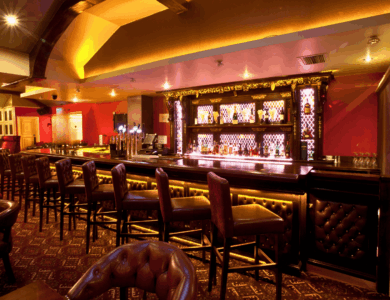 Elegant hotel bar with plush seating and warm lighting, creating a cosy atmosphere for guests.