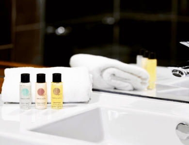 Elegant hotel bathroom with toiletries and folded towels on sink.
