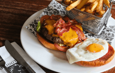 Delicious burger with bacon, cheese, fried egg, and fries at Arlington Hotel bar.