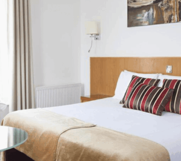 Elegant double room with striped cushions and fresh flowers, ideal for a relaxing stay.