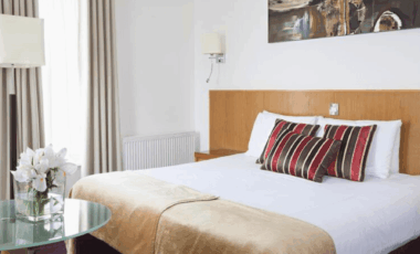 Elegant double room with striped cushions and fresh flowers, ideal for a relaxing stay.