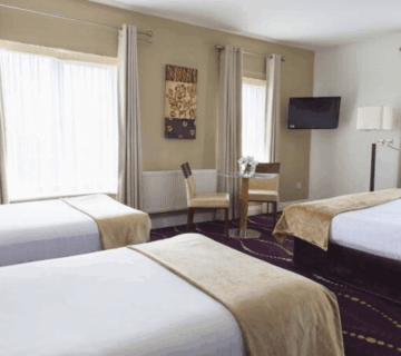 Spacious hotel room with three cosy beds, modern decor, and natural light.