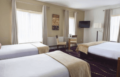 Spacious hotel room with three cosy beds, modern decor, and natural light.