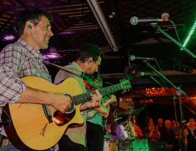 Musicians performing live in a vibrant bar setting, engaging with an enthusiastic audience.
