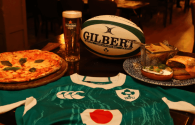Delicious pizza, burger, and beer with a rugby jersey at a cosy bar setting.