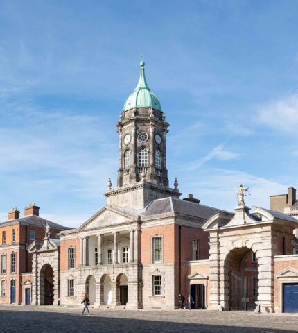 Historic Dublin city centre with a grand clock tower under a clear blue sky.