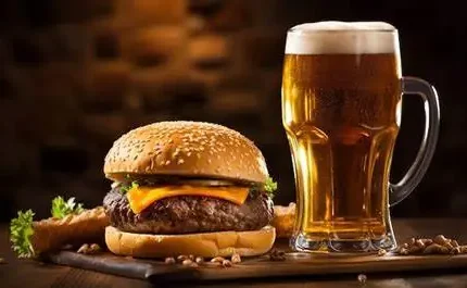 Juicy cheeseburger and frothy beer on wooden board at Arlington Hotel bar.