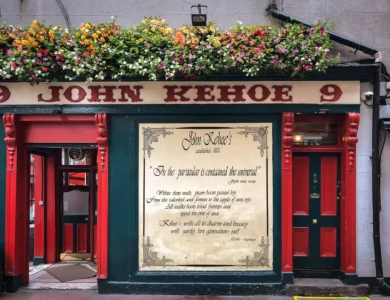 Cosy pub exterior with vibrant flowers and inviting red doors.