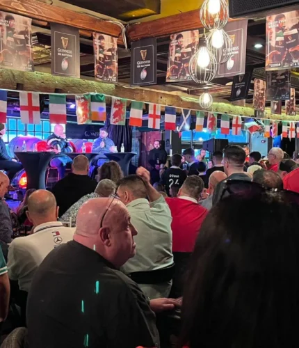 Guests enjoy lively atmosphere at Dublin hotel bar, with flags and rugby decor.