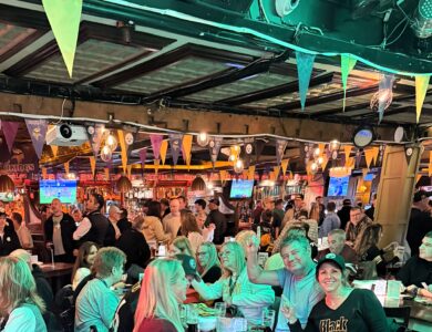 Guests enjoying lively atmosphere in a bustling hotel bar, decorated with colourful bunting.