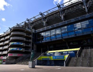 Exterior view of Croke Park stadium with steps and a statue on a sunny day.
