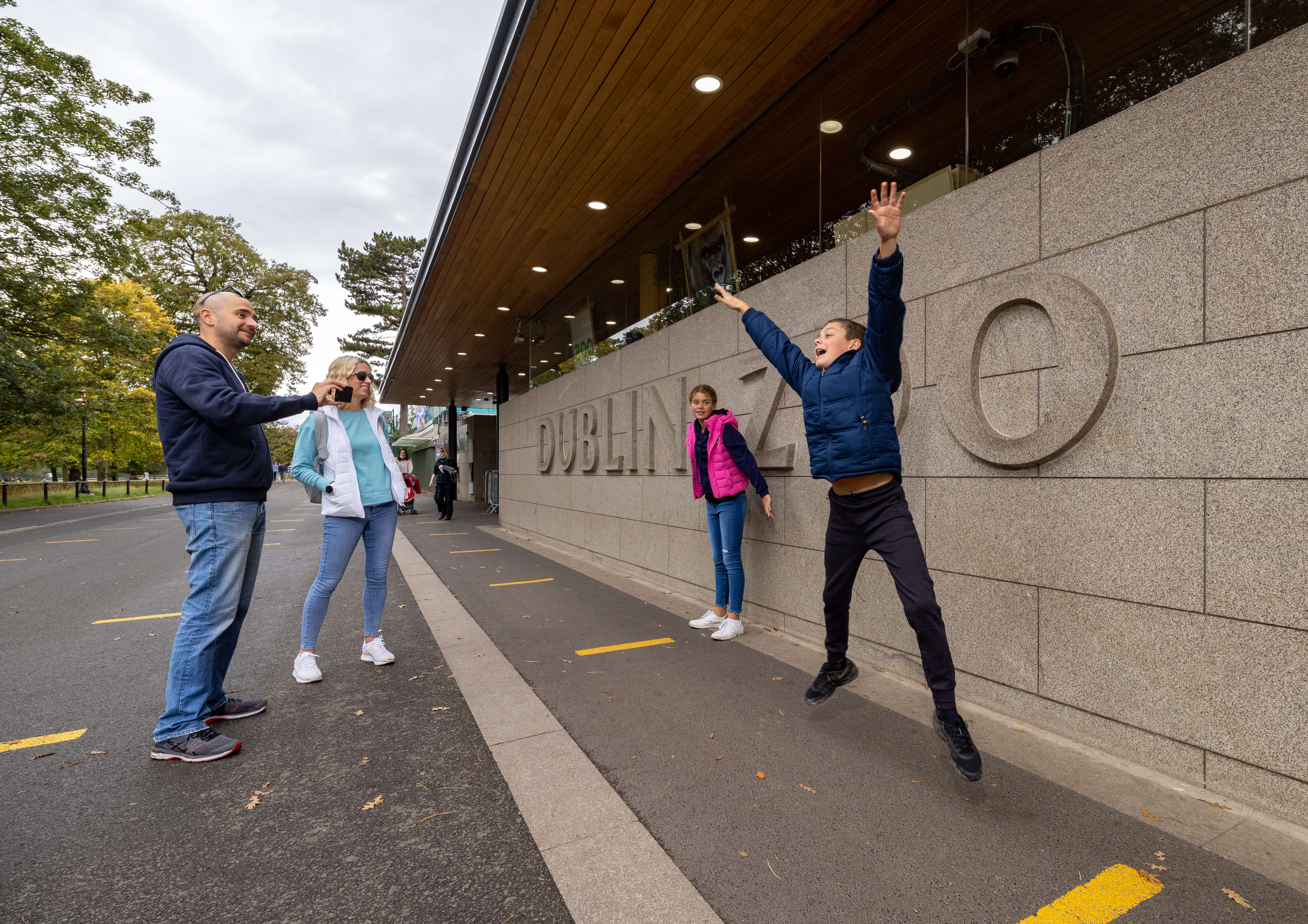 Family enjoying a day at Dublin Zoo entrance with a child jumping joyfully.