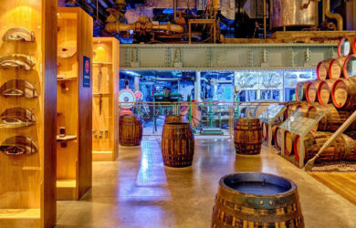 Cosy bar interior with stacked whiskey barrels, warm lighting, and wooden decor.