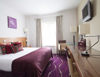 Elegant hotel room with plush bedding, modern décor, and ambient lighting for a cosy stay.