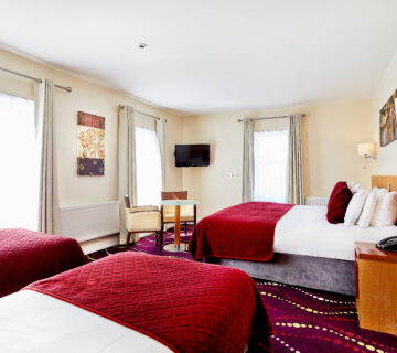 Spacious hotel room with large beds, elegant decor, and bright natural lighting.