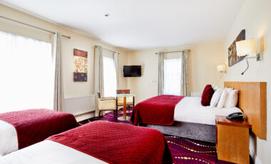 Spacious hotel room with large beds, elegant decor, and bright natural lighting.
