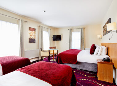 Spacious hotel room with large beds, elegant decor, and bright natural lighting.