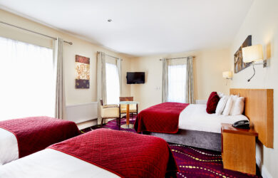 Spacious hotel room with large beds, elegant decor, and bright natural lighting.