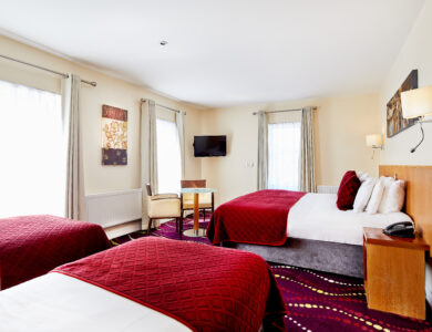 Spacious hotel room with large beds, elegant decor, and bright natural lighting.