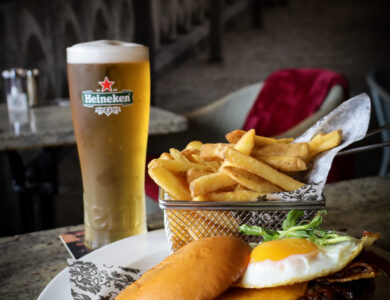 Delicious burger and fries with a chilled pint of Heineken at a cosy bar setting.