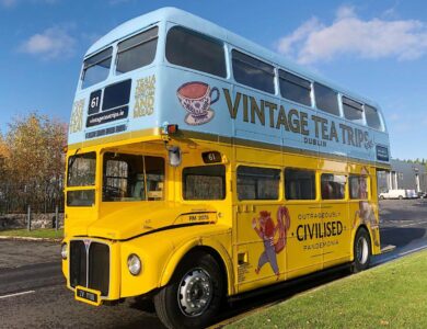 Vintage double-decker bus for tea trips in Dublin, set against a bright sky.