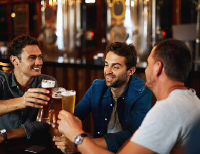 Three friends enjoying drinks at a lively hotel bar.