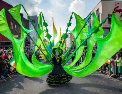 Performer in vibrant green costume at Dublin parade, crowds cheering along streets.