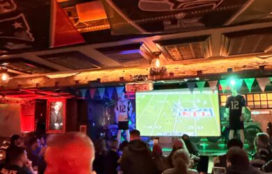 Guests enjoy an NFL game at the Arlington Hotel bar, decked with team flags.