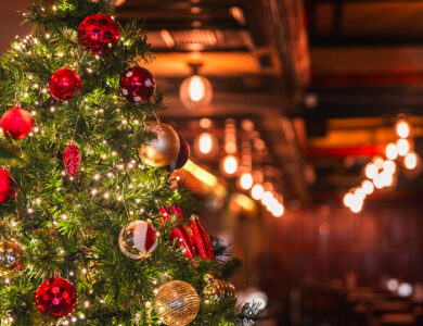 Festive Christmas tree in cosy hotel bar setting, warm lighting creates inviting ambiance.
