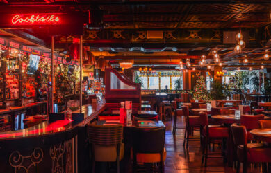 Cozy bar interior with red lighting, festive decor, and inviting seating.