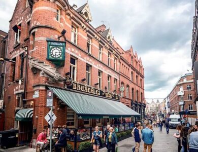 People enjoying a lively day outside Bruxelles Bar on a historic Dublin street.