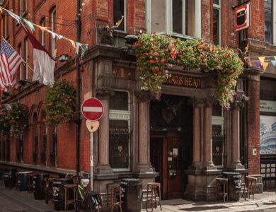 Charming Dublin hotel entrance with flowered facade and cosy outdoor seating.