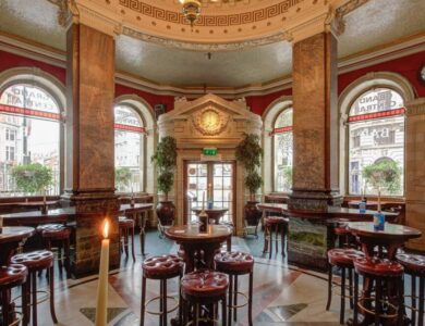 Elegant hotel bar with leather stools and arched windows in a classic setting.