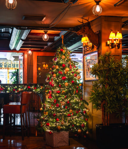 Festive hotel bar with a decorated Christmas tree and warm lighting.