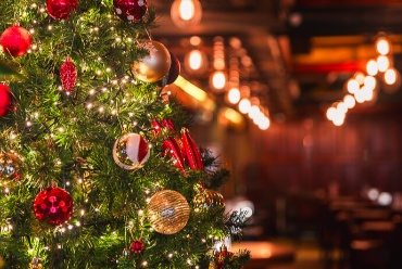 Festive Christmas tree with ornaments in a cosy hotel bar.