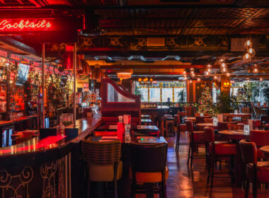 Festive hotel bar with plush seating and neon cocktail sign.