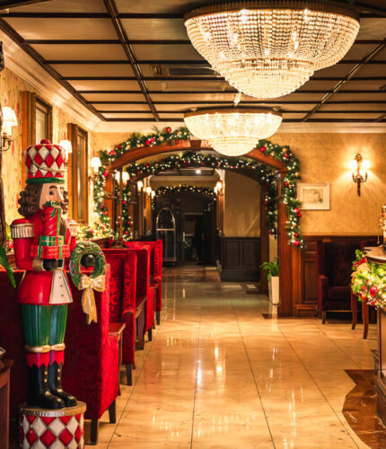 Luxurious hotel lobby with festive decor and elegant chandeliers.