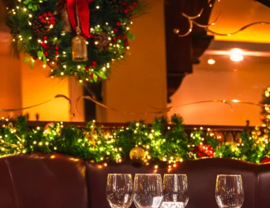 Elegant dining table set with wine glasses and festive wreath in luxurious hotel restaurant.